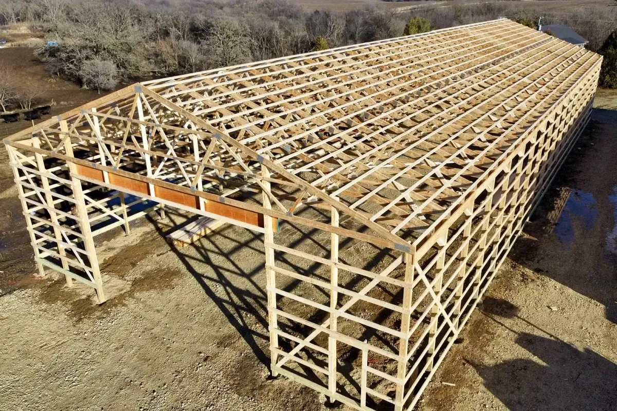 A post-frame building framed out in wood, with roof trusses and purlins set and no skin on it yet.