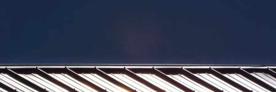 Standing seam metal roof panels raking away against a deep blue sky.