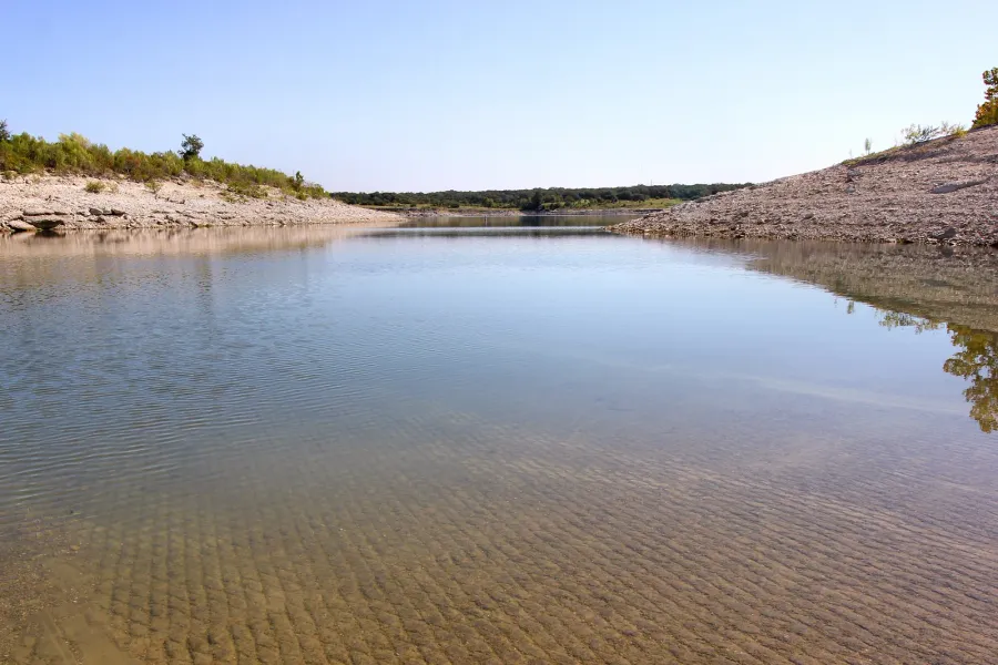 A limestone cove and the low water line at Lake Georgetown, with cedar and oak along the bank, Williamson County.